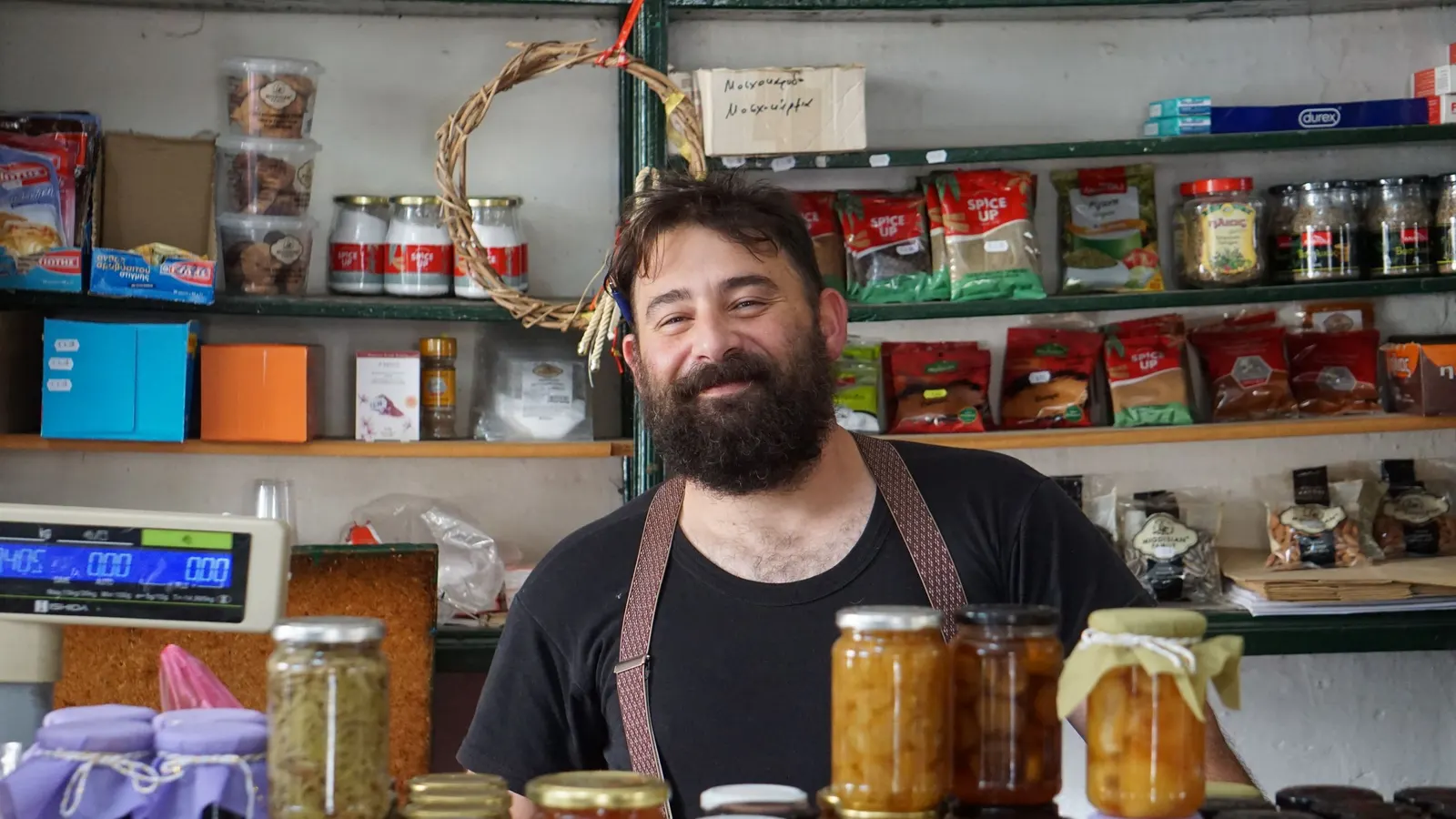A shopkeeper behind shelves of homemade preserves in his own shop.